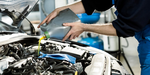 Fototapeta na wymiar Mechanic in car service. Auto mechanic putting oil in a car engine