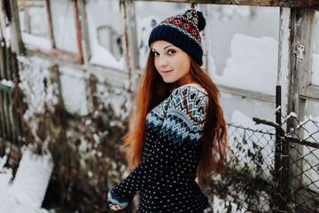 Portrait of beautiful freckled girl with long red hair and cute charming smile wearing gray stylish hat looking and smiling at camera standing against studio wall background. Isolated shot, horizontal