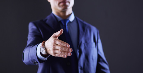 Portrait of successful cheerful cute young man presenting new product, showing copy spase on her palm on grey background