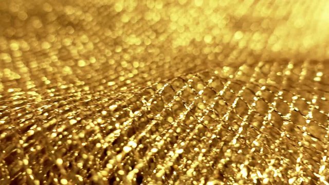 Macro video of gold jewelry net, sparkling small rectangular meshes. Abstract background, shallow depth of field