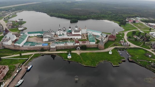 Smooth cinematic flyby of the Solovetsky monastery from the side of the White sea with a view of the Saint Lake on a cloudy day with soft lighting. Solovetsky monastery is an old (1420) ROC monastrey