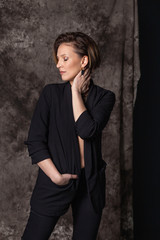 vertical closeup portrait of a beautiful european woman in black suit on gray background