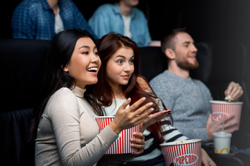 Weekend getaway. Smiling girls enjoying their movie night in cinema