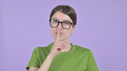 The Beautiful Woman putting Finger on Lips on Purple Background