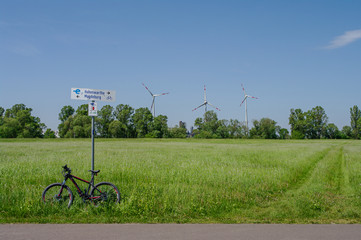 Beautiful farm landscape, wind turbines to produce green energy and bicycle in Germany, summer, blue sky