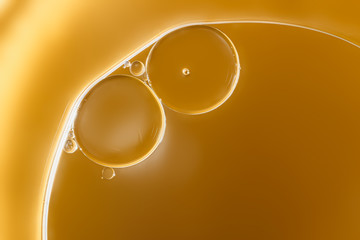 Close up ,oil drops floating on water surface  ,With  yellow background
