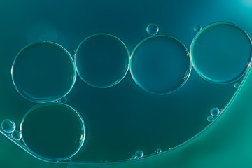 Oil drops floating on water surface ,With cyan background ,close up