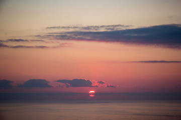 Atardecer con el sol poniéndose con vista de océano atlántico y cielo color rojo con nubes