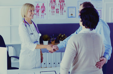 Fototapeta premium Female doctor handshaking a patient's hand and smiling