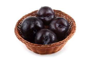 Black plums on wicker plate
