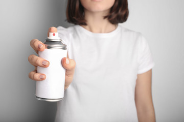 Woman holds spray can in hands on grey background