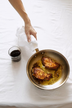 Female hand holding a pan with fried white fish steakes