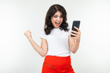 Naklejka premium joyful girl with a phone in her hands on a white background with copy space