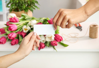 Hand of client and florist holding a business card