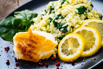 Risotto with fried cod on wooden background