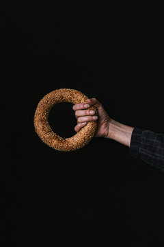 A Hand with a Bagel on a Black Background