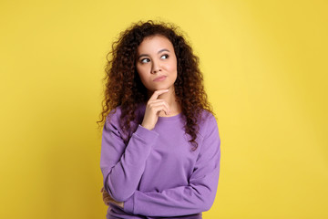 Pensive African-American woman on yellow background. Thinking about difficult question - obrazy, fototapety, plakaty