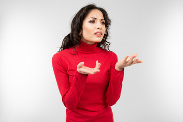 brunette in a red sweater is trying to explain something on a white studio background