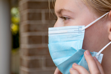 A girl wearing disposable face mask to prevent spreading of the viruses. Coronavirus and COVID-19...