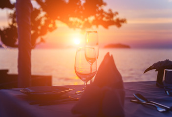 Fototapeta na wymiar Wine glasses on the table of bar. Sunset over the sea