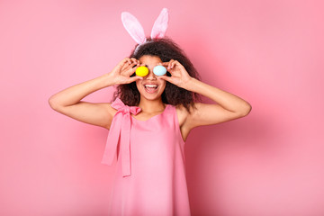 Young African with rabbit ears on a pink background. Easter concept