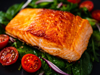 Fried salmon steak and vegetables on wooden table