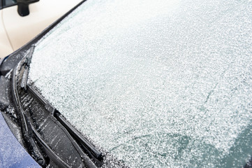 Snow covers car windshield. Concept of road safety in winter.