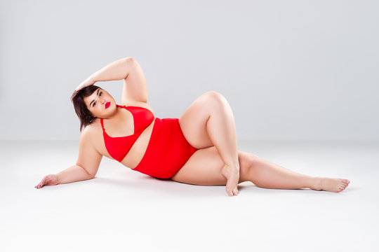 Plus size fashion model in red swimsuit, fat woman in lingerie on gray background