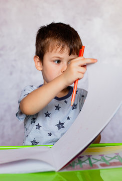 Little boy drawing with color pencils. Boy, drawing a picture for fathers day. Small boy draws at the table.