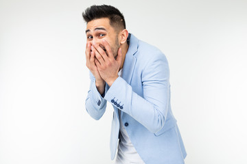 handsome man in classic style laughs covering his face with his hand on a white studio background