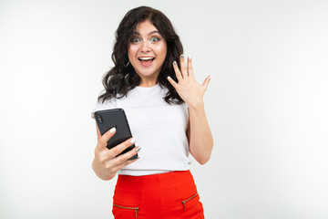 Naklejka premium happy girl dancing with joy realizing about winning in a draw on the Internet holding a phone in her hand on a white background