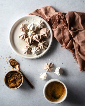Chocolate and vanilla meringue puffs on a white dish with hot chocolate and a brown cloth