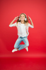 Modern child. Perfect sound. Never ending joy. So much fun. Girl listening music modern gadget. Kid happy with wireless headset dancing jumping. Stereo headphones. Kid using modern technology