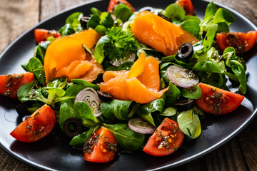 Salmon salad - smoked salmon and vegetables on wooden background