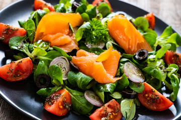 Salmon salad - smoked salmon and vegetables on wooden background
