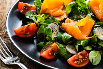 Salmon salad - smoked salmon and vegetables on wooden background