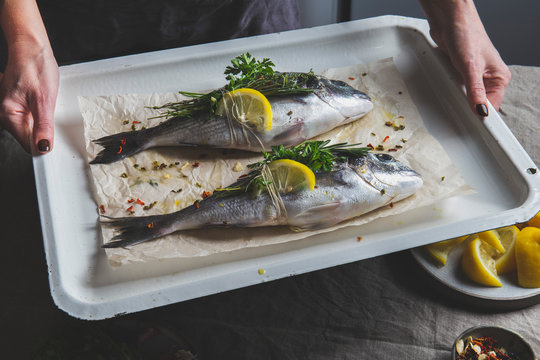 Women holding a bakind tray with dorada or bream