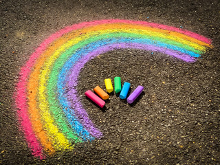 Colorful chalk sticks and a rainbow drawn on a sidewalk © Sabrina