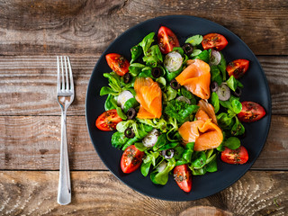 Salmon salad - smoked salmon and vegetables on wooden background