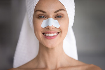 Close up head shot happy attractive lady with cleansing strip on nose looking at camera. Portrait...