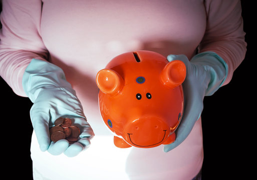 concept image topic coronavirus crisis, piggy bank, hands in gloves and euro coins
