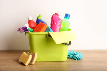 Many cleaning products on wood table and white wall