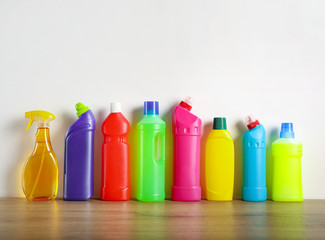 Many cleaning products on wood table and white wall