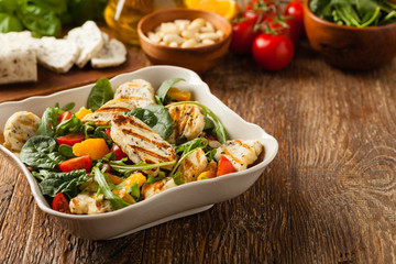 Traditional Greek salad with grilled Halloumi cheese with basil. Front view.