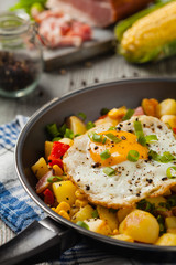Traditional American hash with fried eggs. Front view.