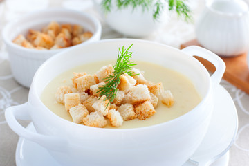 Mashed potato soup with homemade croutons in a white soup plate, horizontal