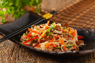 Oriental salad with rice noodles, chicken and mint. Front view.