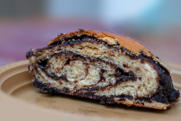 Yeast dough cake, roll shape, filled with chocolate flavored, homemade baking, handmade, on a gold plate, blurred background.