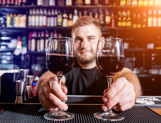 Bartender pours red wine into a glass. Sommelier. Restaurant. Nightlife