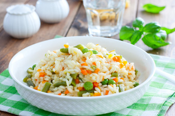 Italian risotto with vegetables - peas, beans, carrots, peppers on a white plate, selective focus